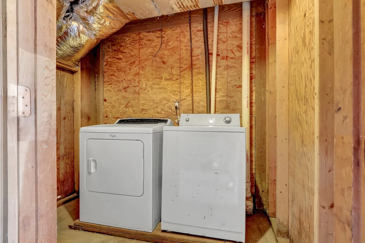 An interior shot focusing on a washing machine and dryer side by side. The appliances are clean and modern, set in a dedicated laundry area that feels organized and functional, inviting guests to refresh beachwear or pet gear.