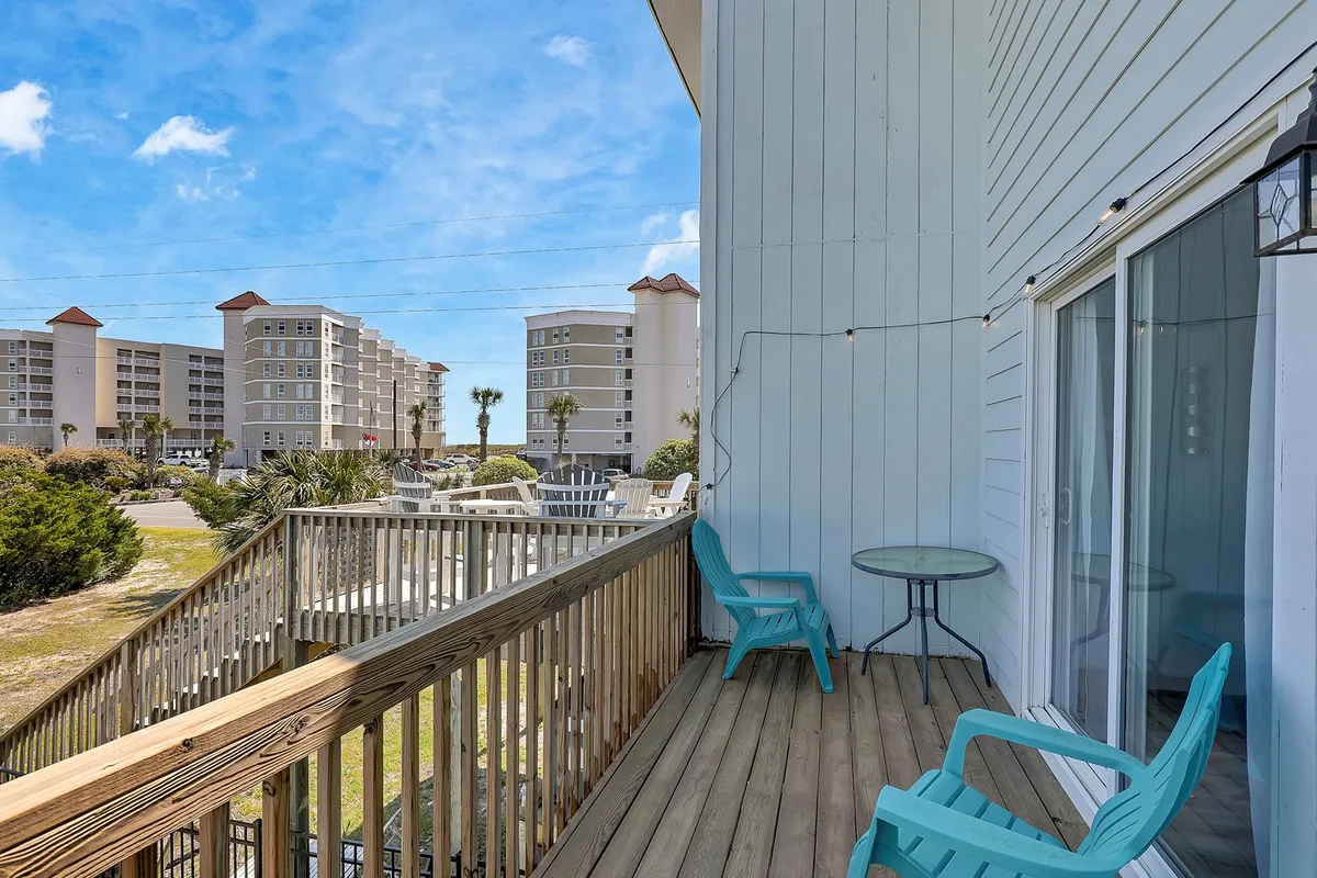 An airy balcony setting featuring comfortable outdoor seating, palm trees, and partial ocean views. The space invites relaxation and socializing in a casual, private atmosphere while soaking in the coastal surroundings.