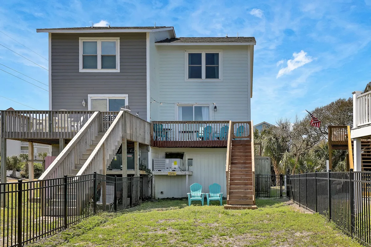This image features a welcoming deck with blue chairs, a staircase leading up, and a clearly visible fenced yard. The scene highlights outdoor relaxation spaces, the safety of a fenced area, and invites the viewer to imagine enjoying both the deck and yard.
