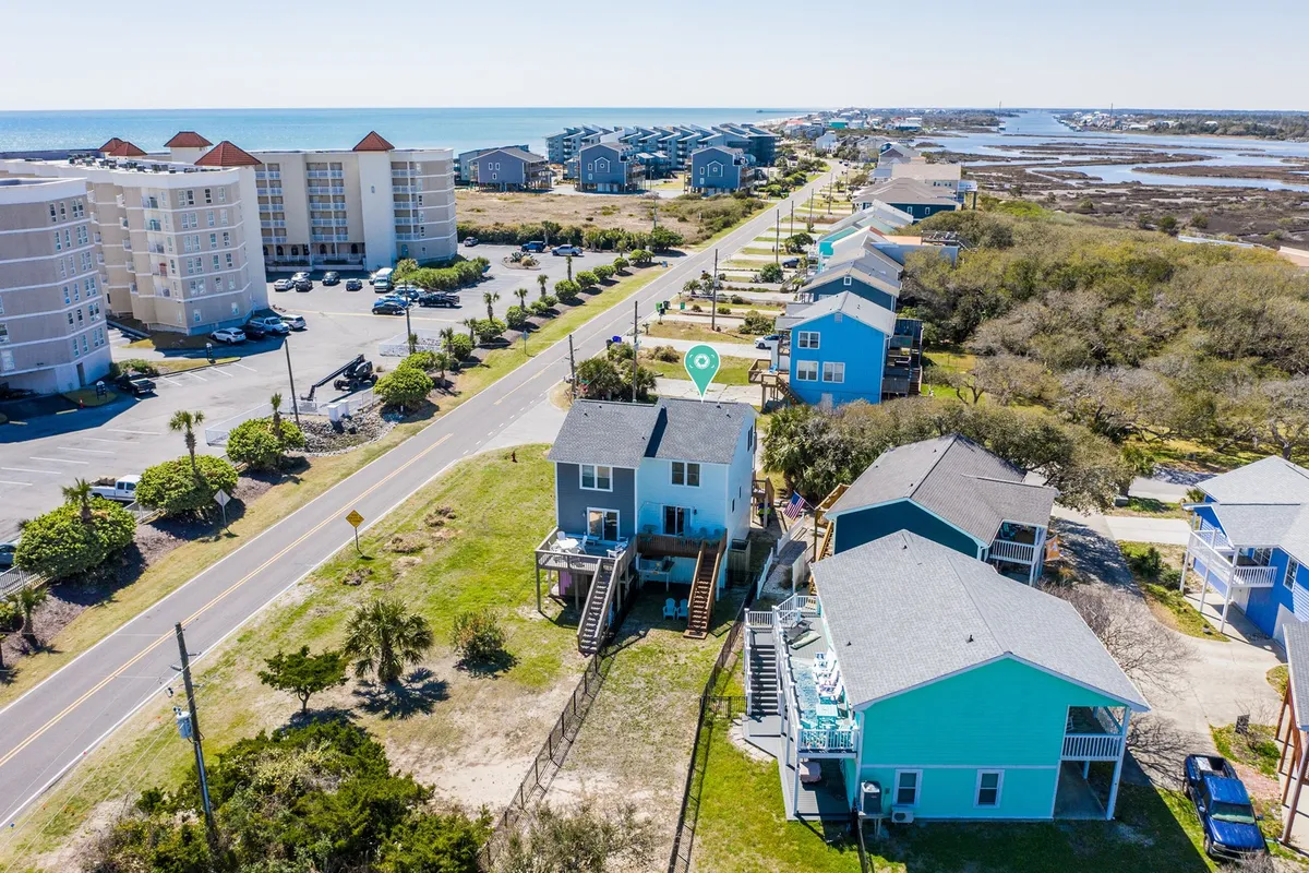 This photo shows the beachfront lined with colorful houses and a road leading directly to the sand. The relaxed mood and visible walking paths invite exploration, picnics, and leisurely strolls by the shoreline.